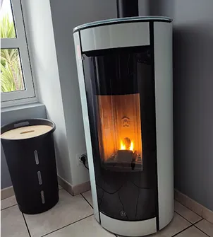 Poêle à granulés blanc moderne allumé dans un coin de pièce, à côté d'une fenêtre à Sainte Gemme la Plaine près de Luçon en Vendée 85